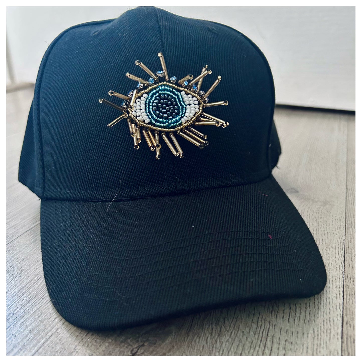 BLACK CAP WITH EVIL EYE EMBELLISHMENT